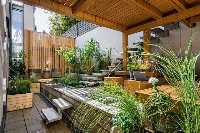 a high-end home entrance way with lots of plants and minimalist cement and wood decor